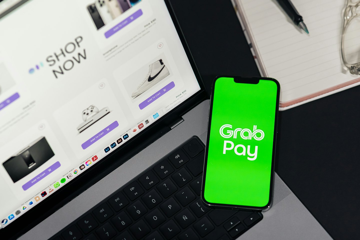 Laptop con sito di e-commerce accanto a smartphone con app di pagamento.