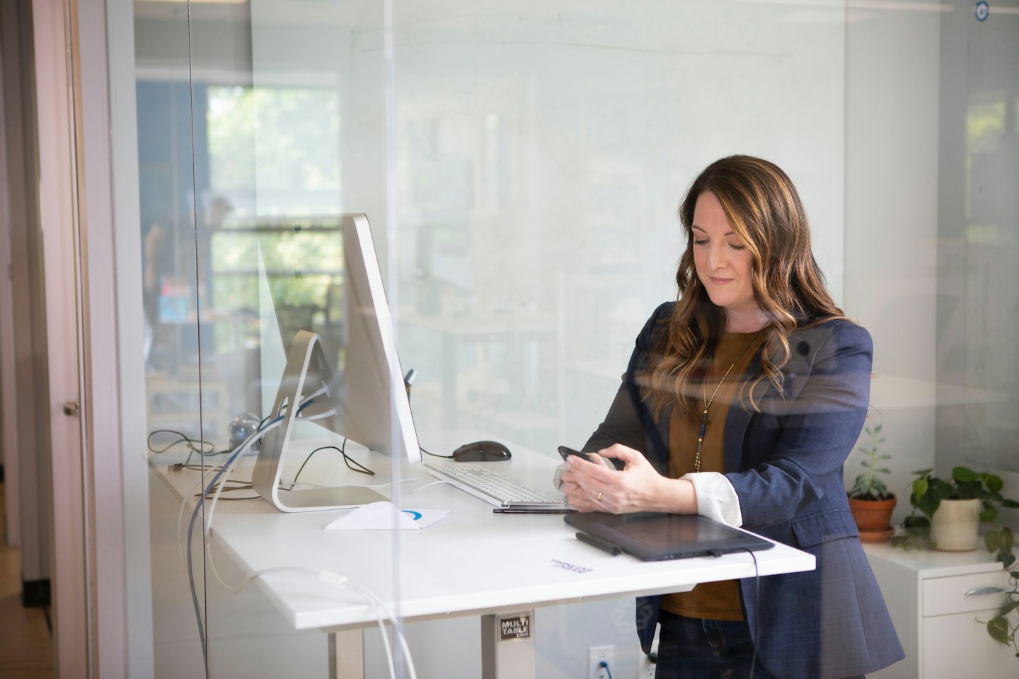 Donna che usa lo smartphone a una scrivania moderna in ufficio.