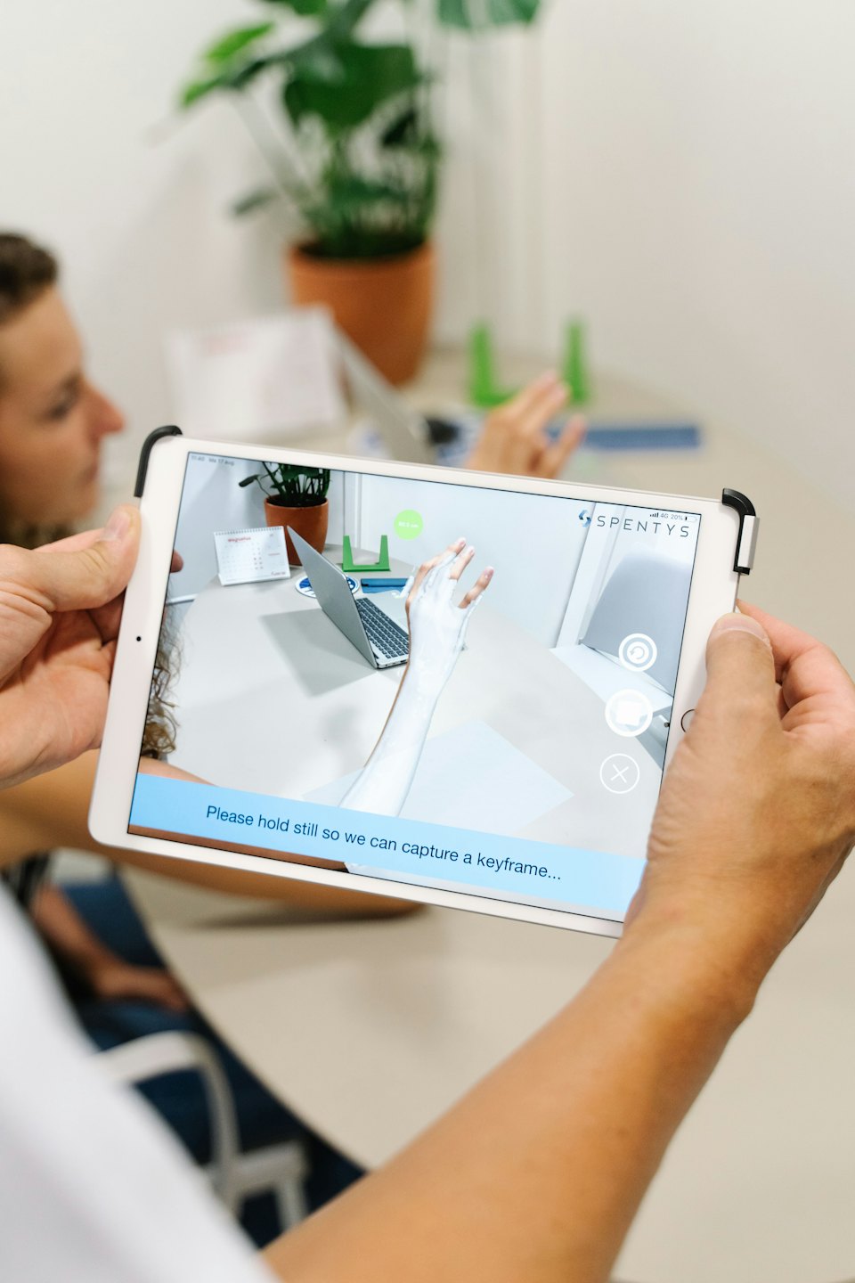 Persona usa un tablet per mostrare un modello AR di un calco sulla scrivania.